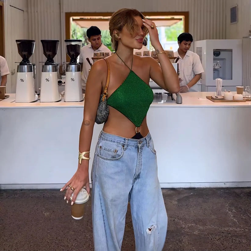 Woman in a green top and blue jeans standing in a coffee shop.