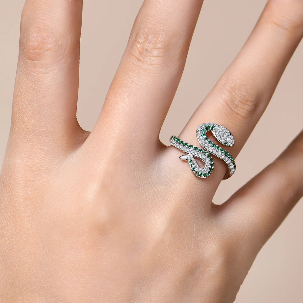 Serpentine ring with green gemstones on a hand against a beige background